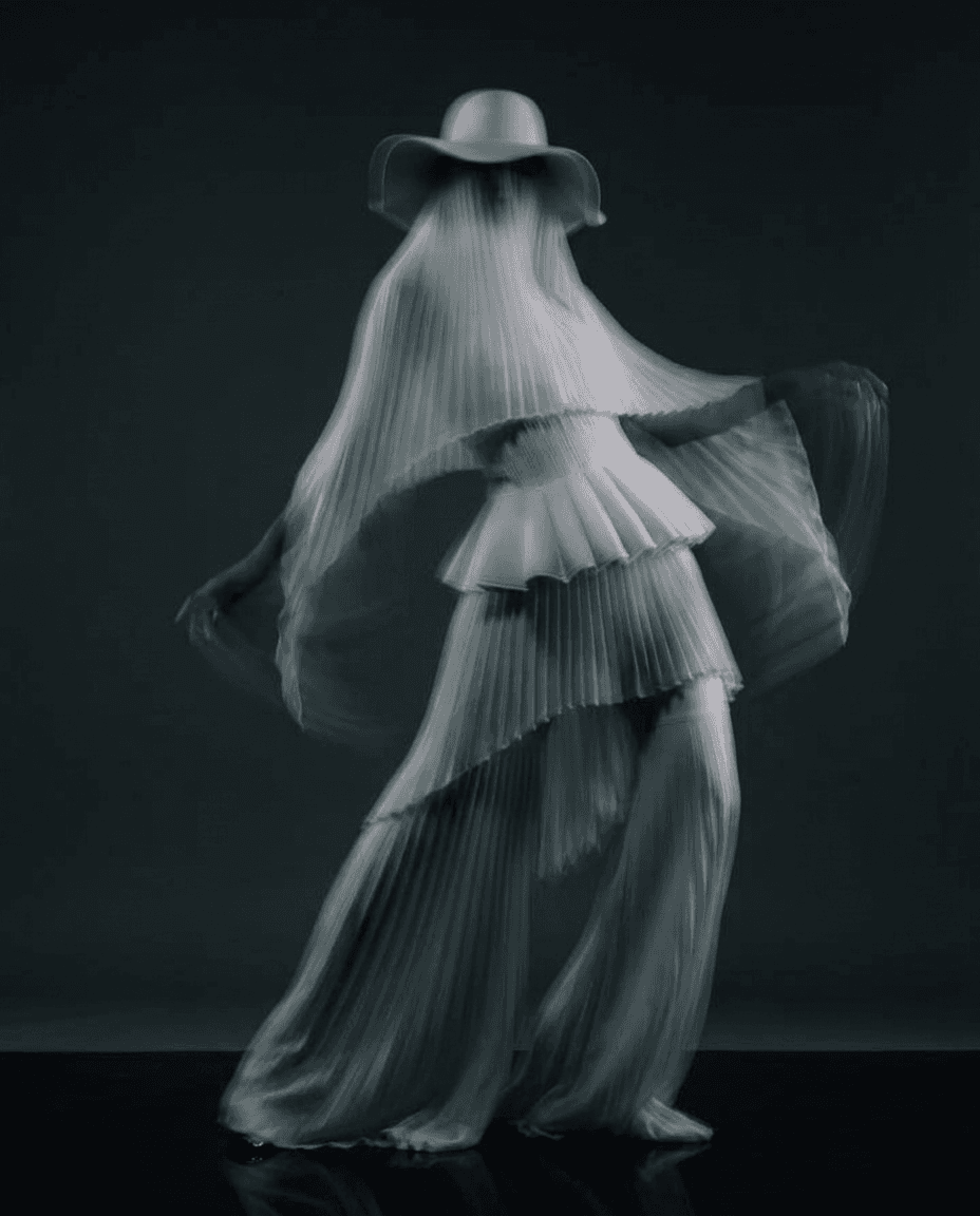 A woman in a flowing pleated garment in black and white.