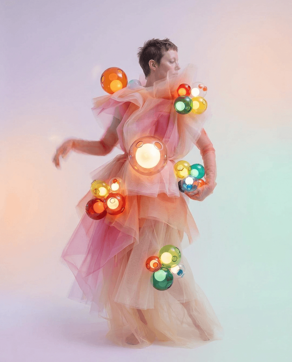 A woman in flowing fabric with colourful, translucent spheres in a whimsical portrait.