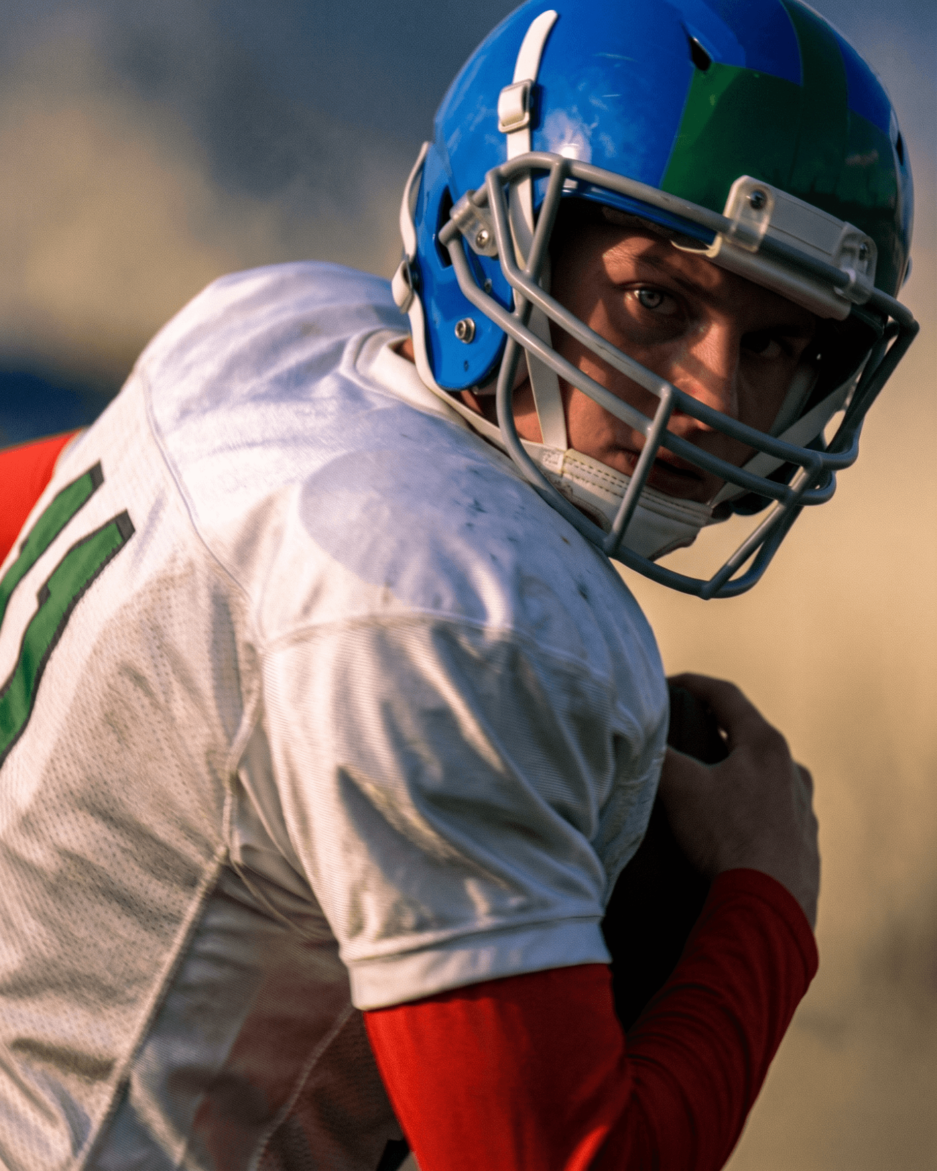 Close-up of a football player showing focus and determination with a blurred background.