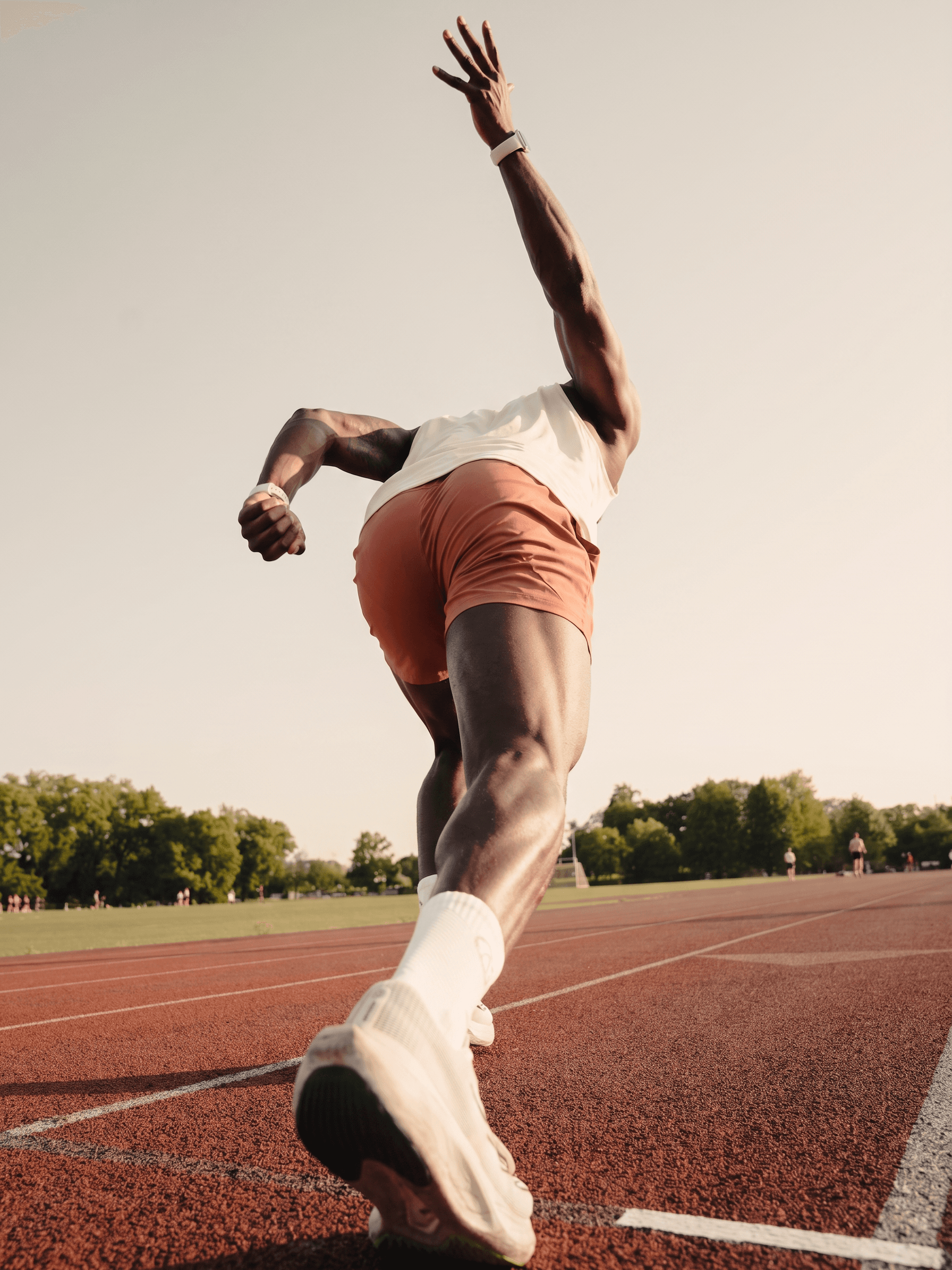 Male runner captured mid-stride on a track in warm tones.