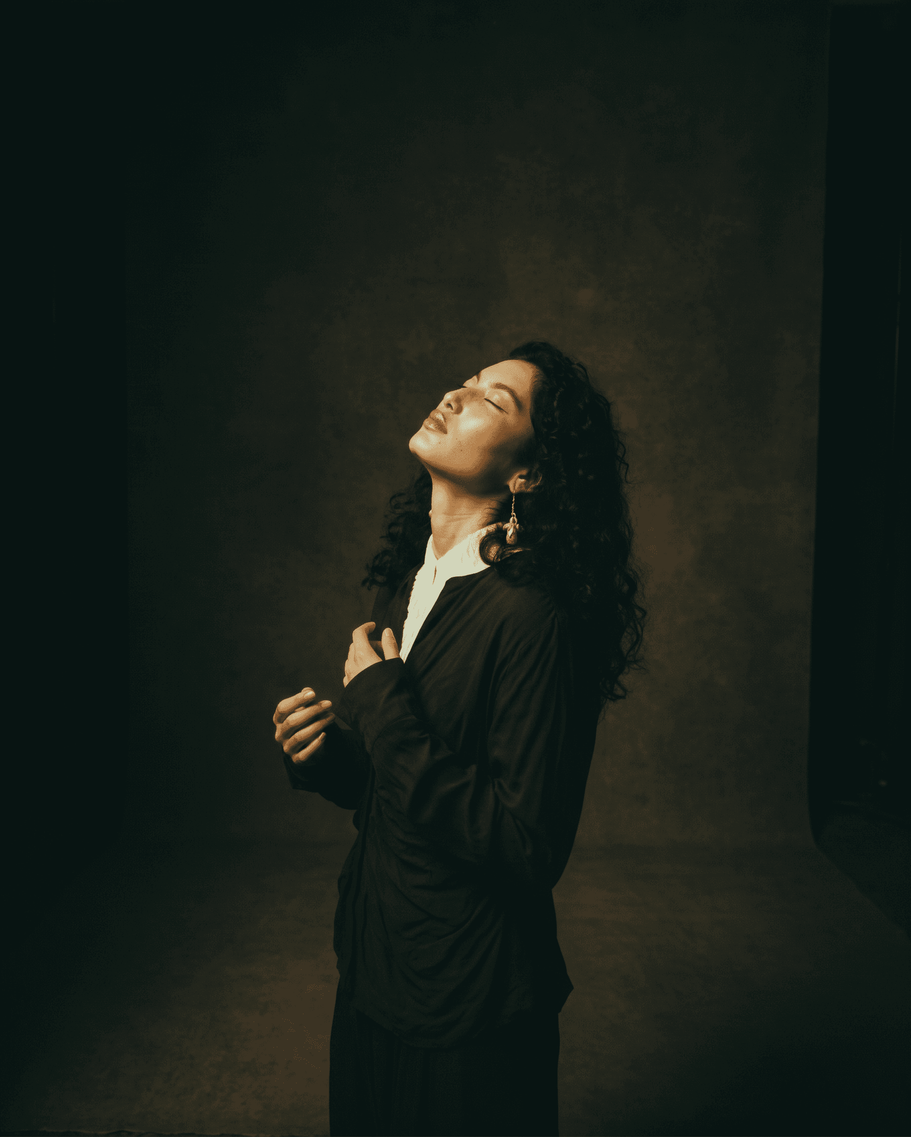Portrait of a woman with curly hair in a studio with moody lighting.