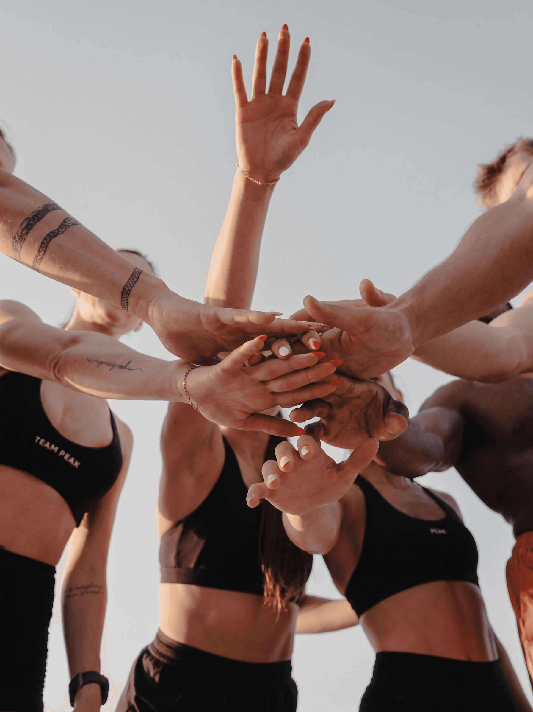A diverse group of individuals with hands raised together in a united gesture.