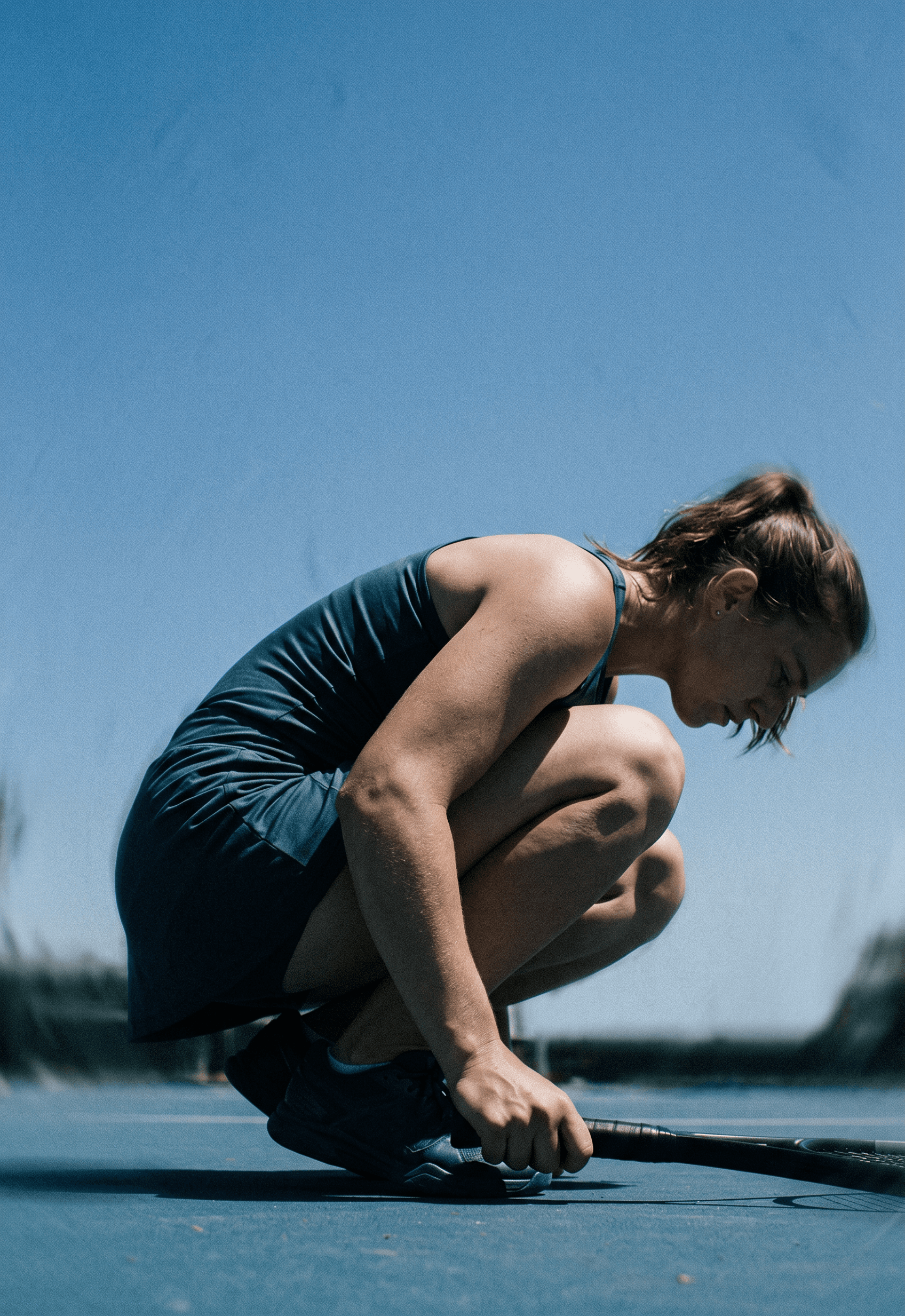 A woman crouches on a tennis court, ready to make her next move.