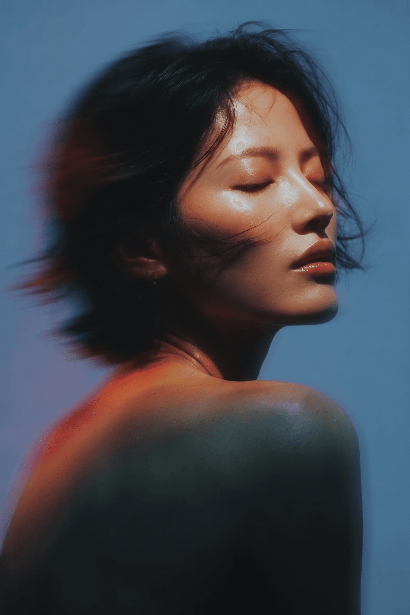 Close-up portrait of a woman with closed eyes in soft lighting.