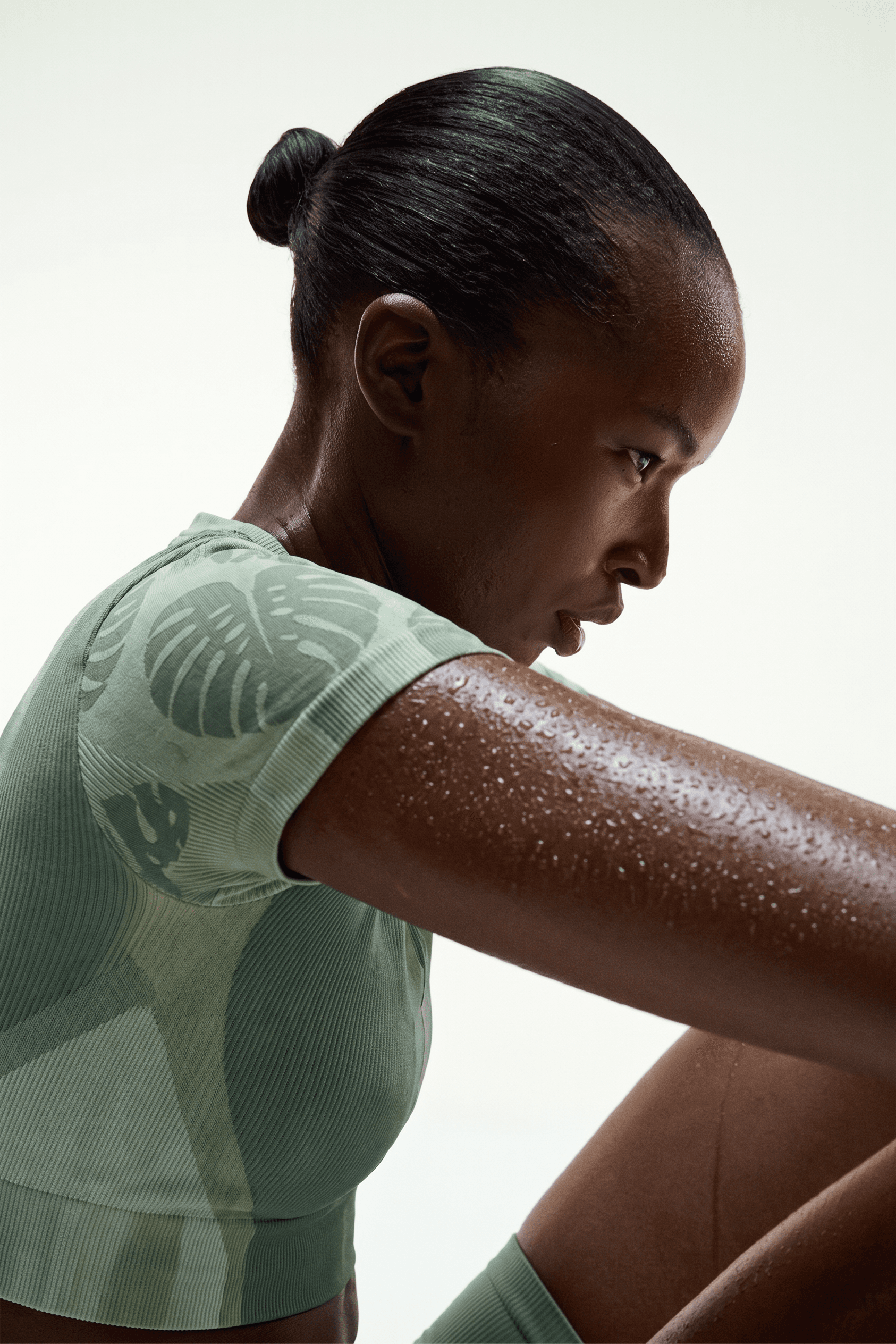 Profile portrait of a woman with a ponytail and athletic build, set against a clean background.