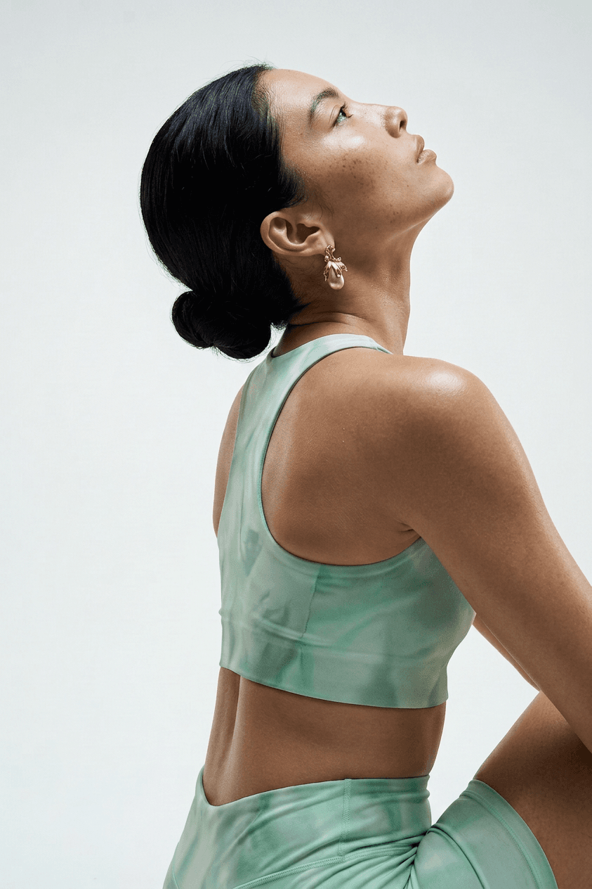 Woman in a green marbled athleisure outfit, posing against a minimalist background.