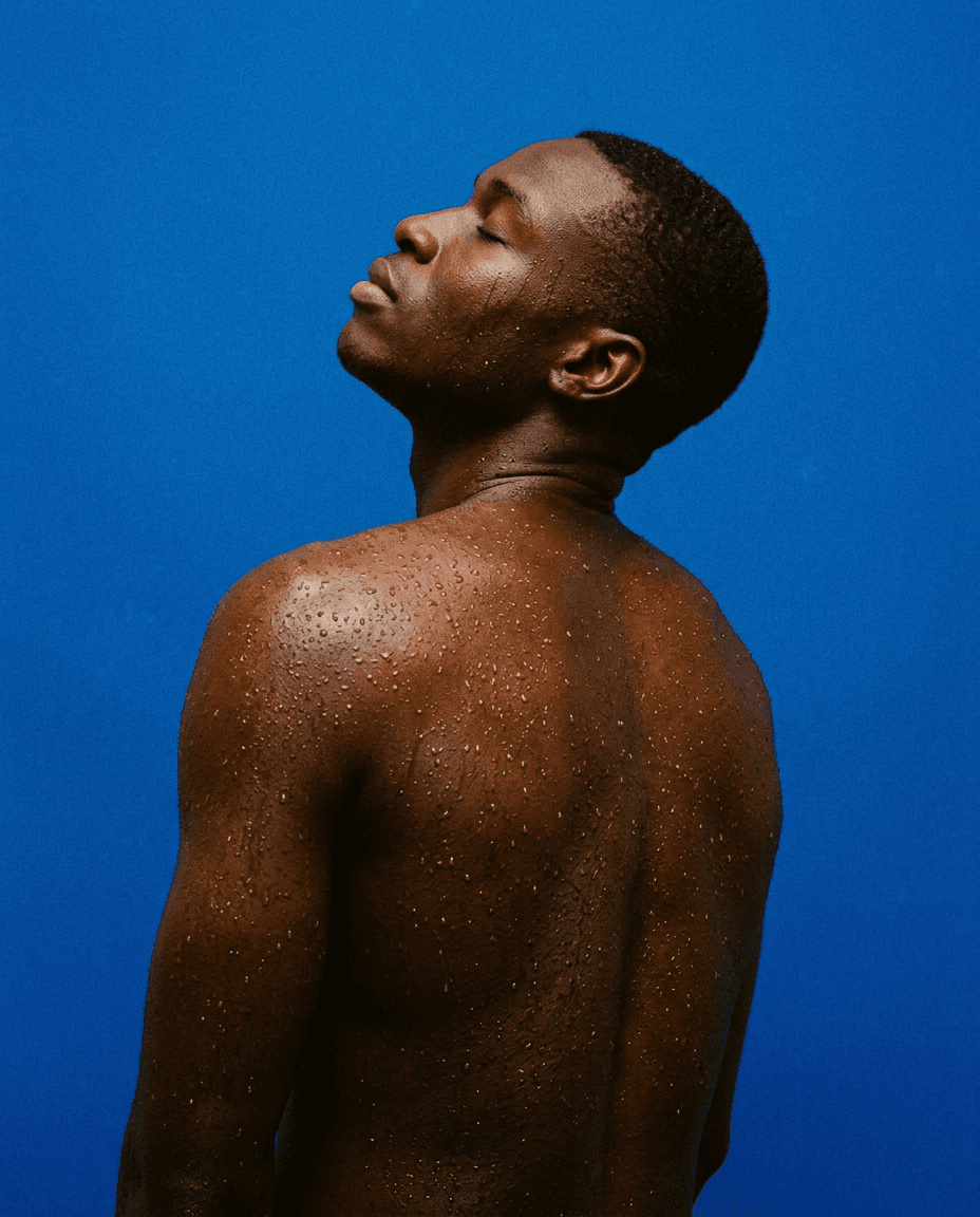 Close-up portrait of a man with wet skin against a blue background.