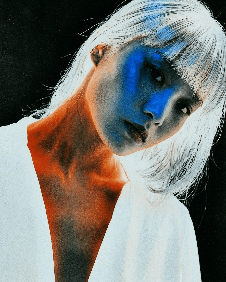 Portrait of a woman with short light-coloured hair in vibrant blue and orange lighting.