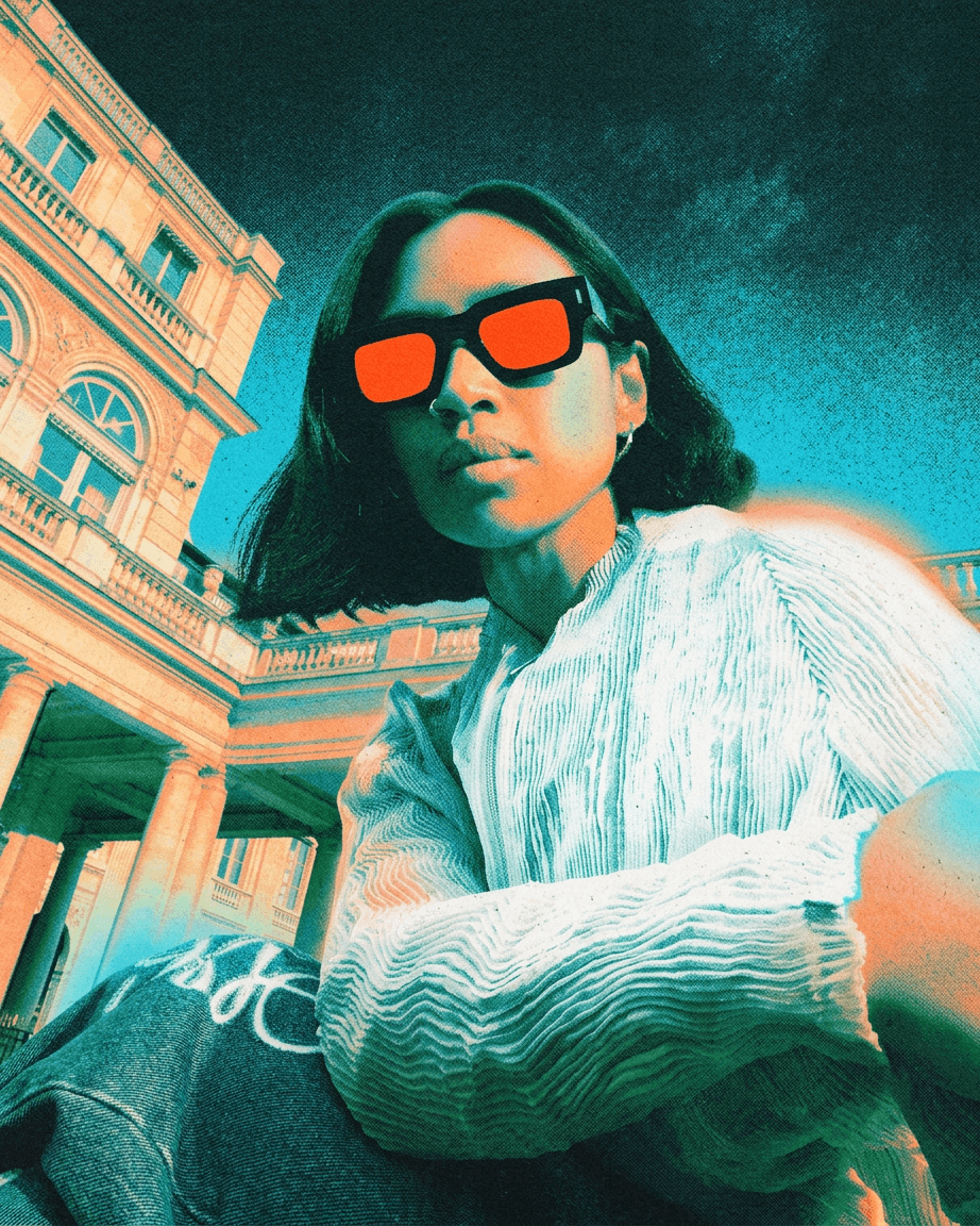 Portrait of a woman in sunglasses sitting by a historical building.