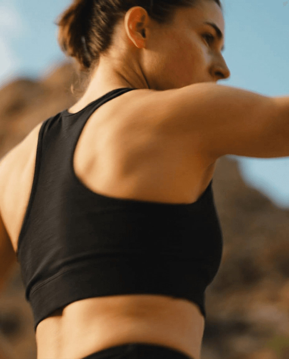 Woman in athletic attire exercising outdoors with a focused expression.