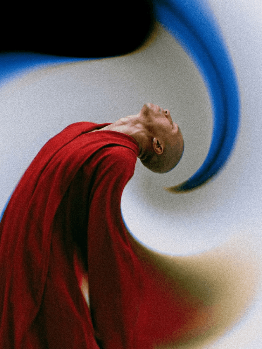 Man in a red robe tilting his head back with a swirling blue and cream background.