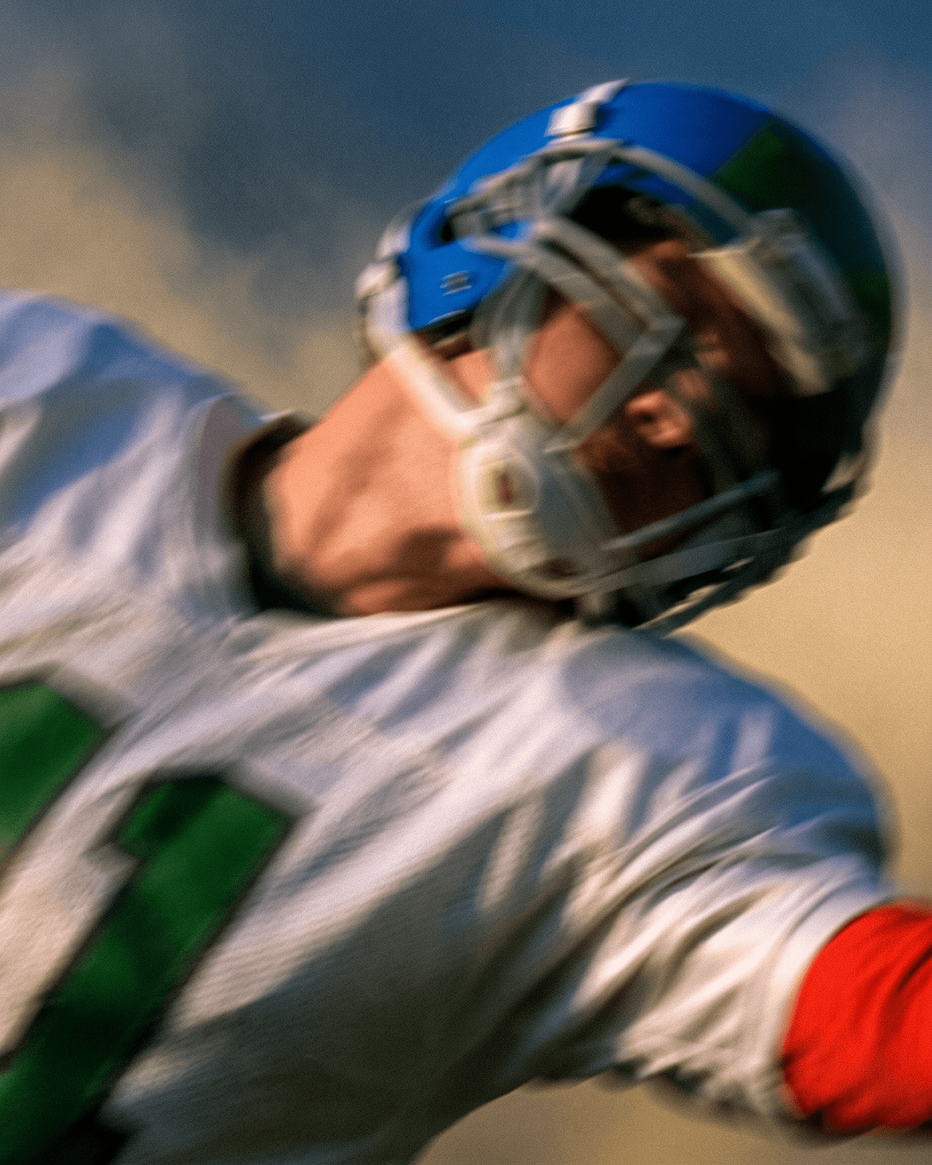 Football player captured mid-action with green and blue tones.