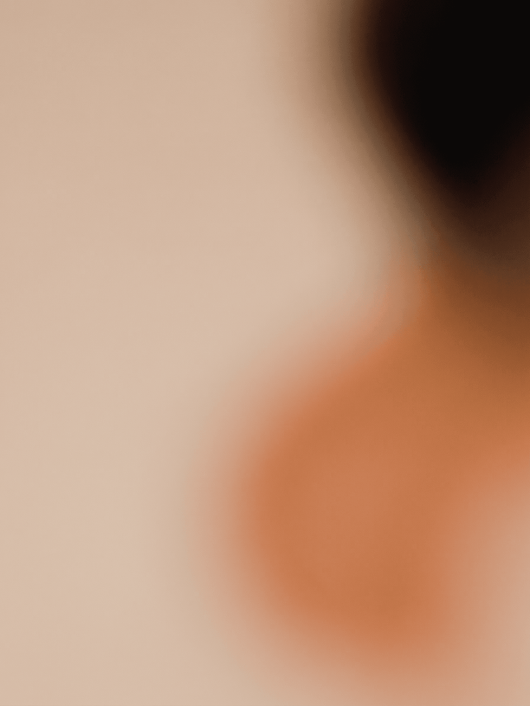 Close-up of a figure's shoulder in soft focus with warm tones.