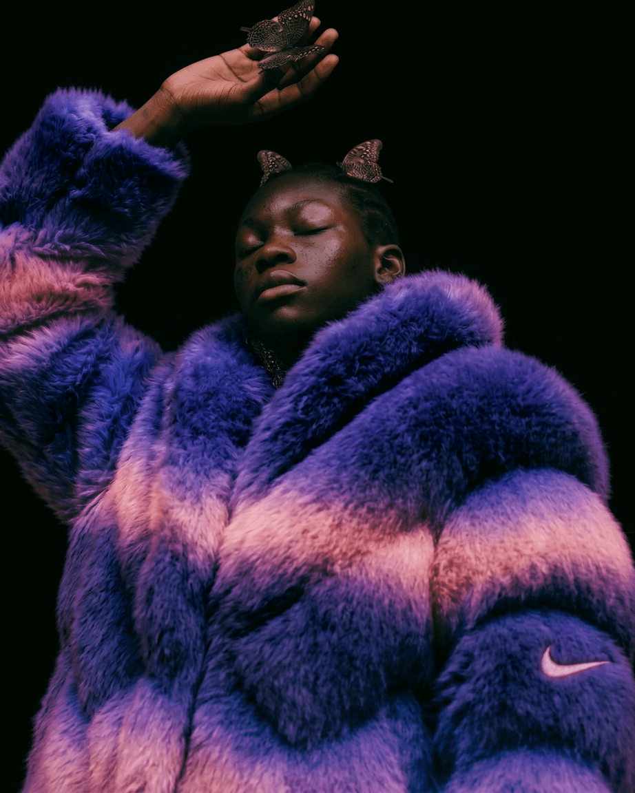 Close-up of a woman in a multicoloured fur coat with butterfly hair accessories.