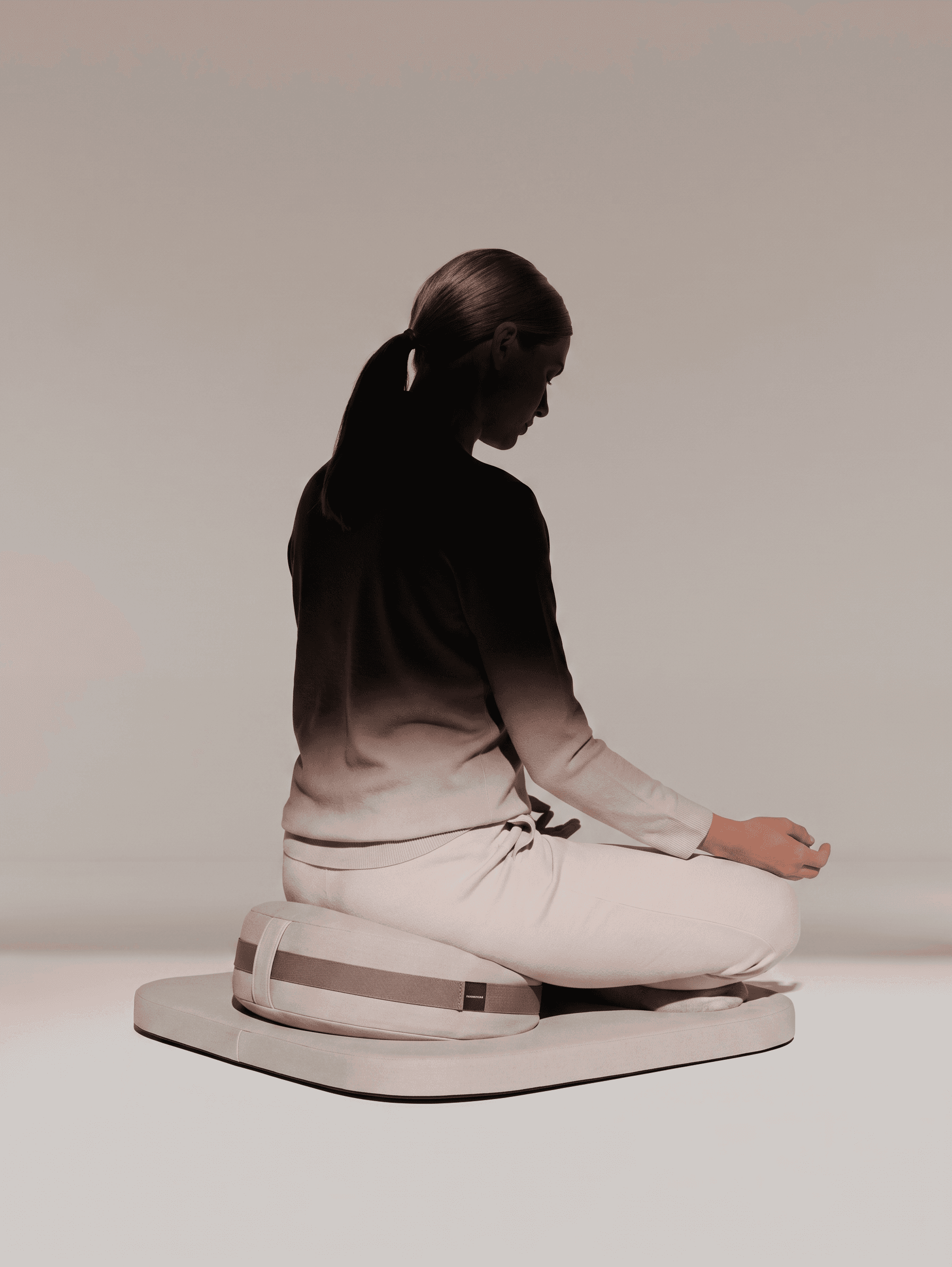 A woman sitting cross-legged on a cushion, meditating in soft beige and gray tones.