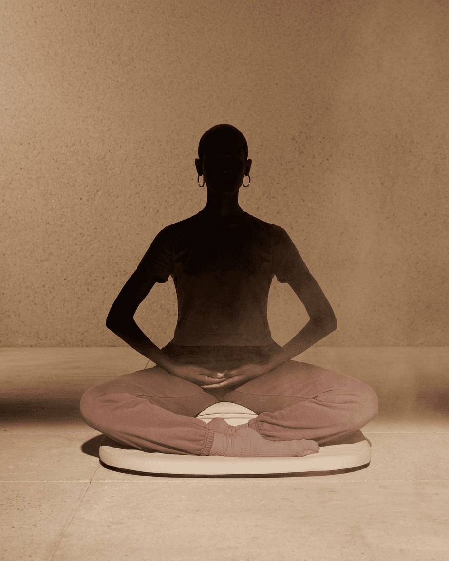 Silhouetted figure meditating with soft dust particles in the air.