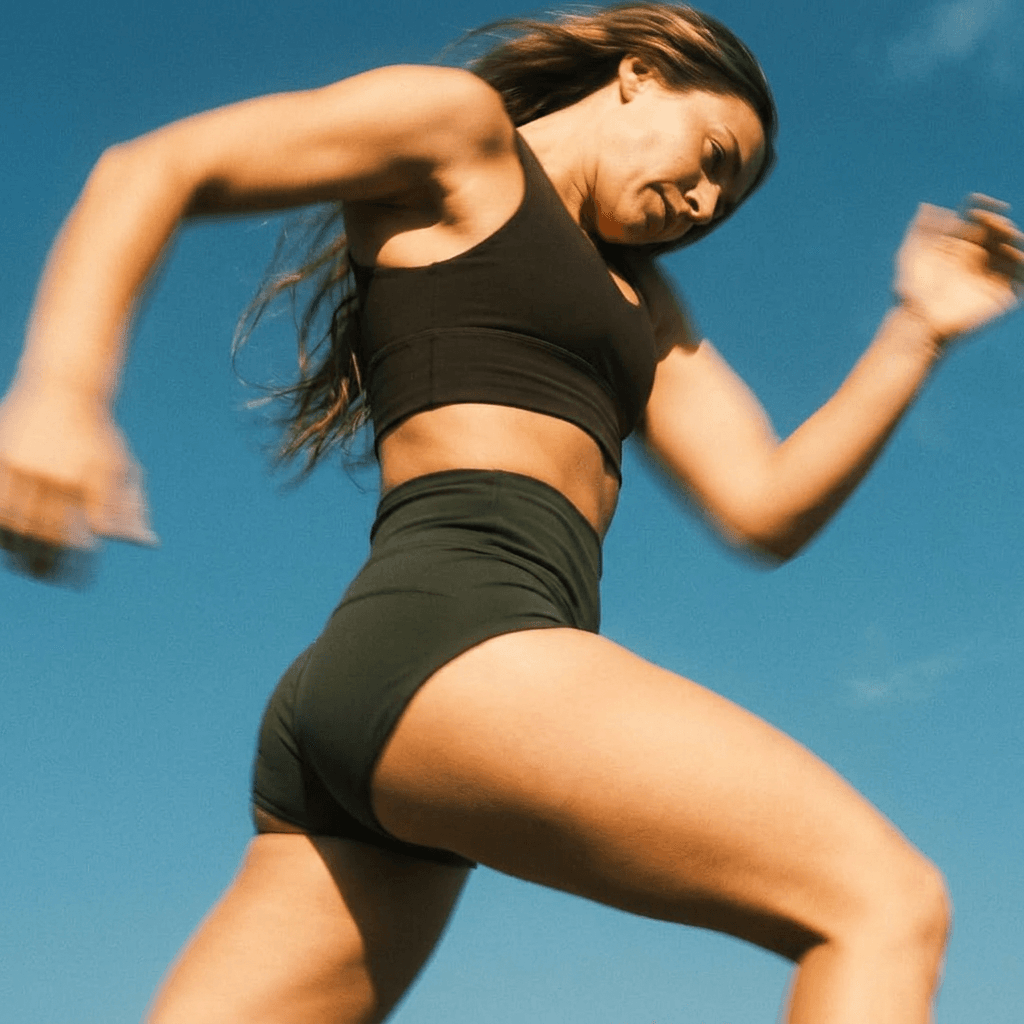 A woman running with a clear blue sky in the background.