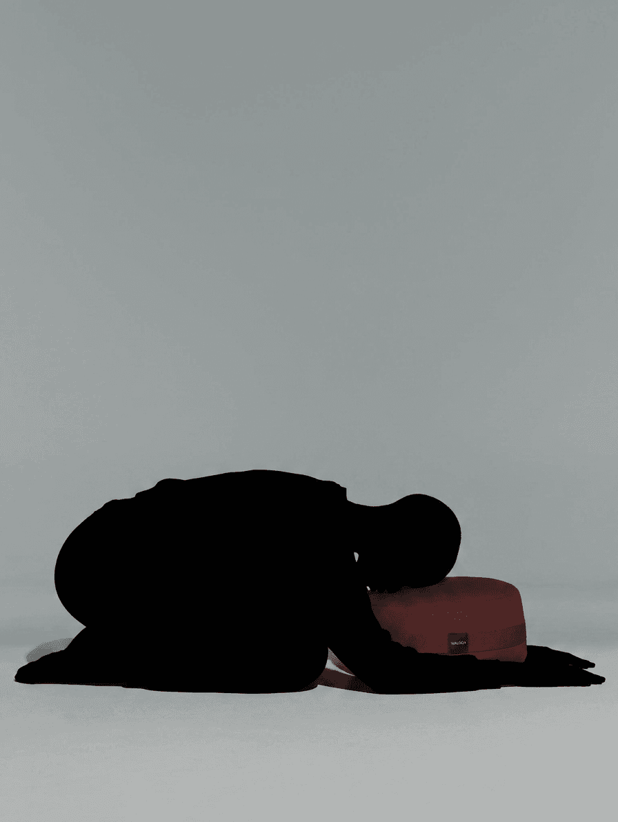Silhouette of a person kneeling beside a rectangular object in a minimalist style.