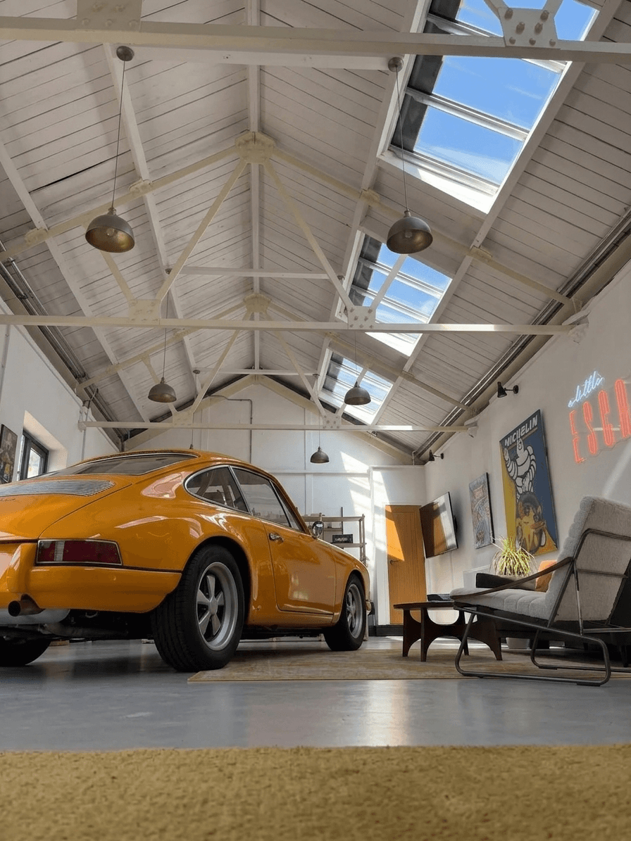 Vintage orange sports car inside a spacious modern loft with natural light.