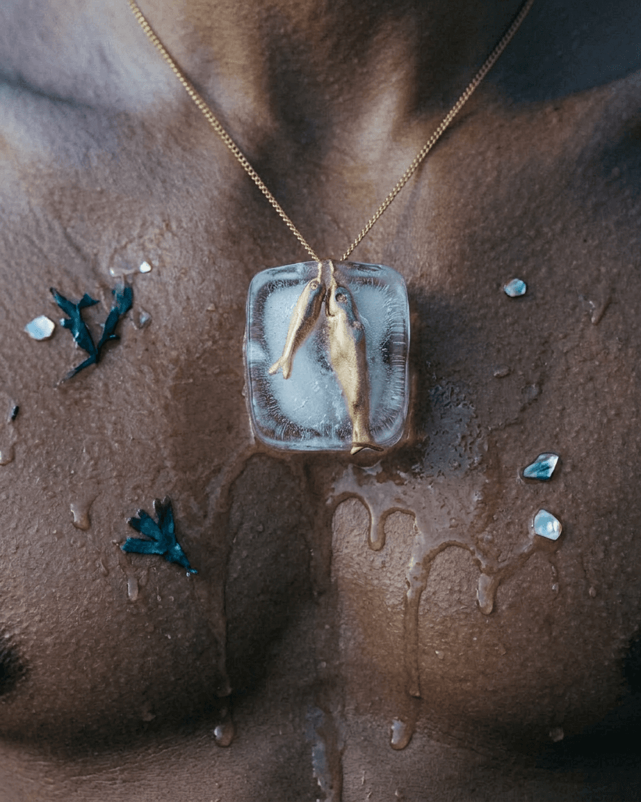 Close-up of a man's chest with an iced fish pendant and droplets.