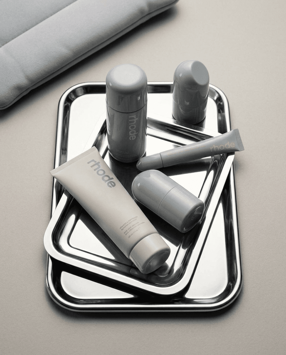 Skincare products arranged on metallic trays in soft grey and white colours.
