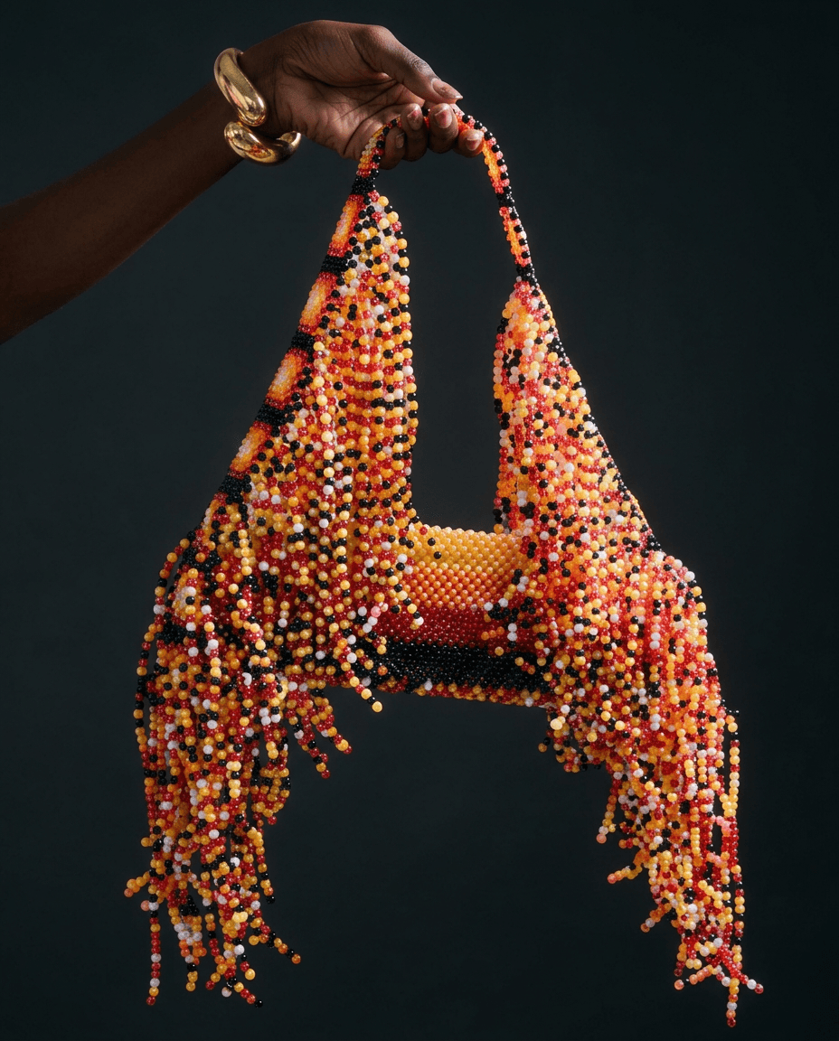 A vibrant beaded handbag with cascading fringe in orange, yellow, and black.