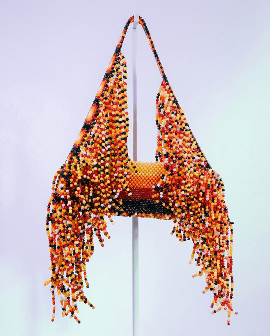 Textile artwork featuring a handbag with colourful beads and a flowing fringe.