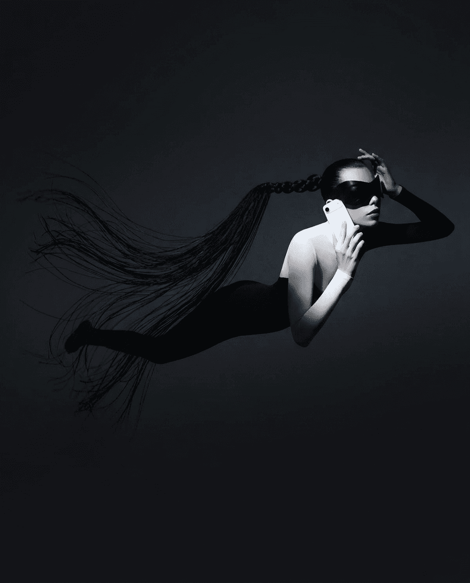 A figure in a monochrome bodysuit suspended underwater, holding a phone with flowing hair trailing behind.