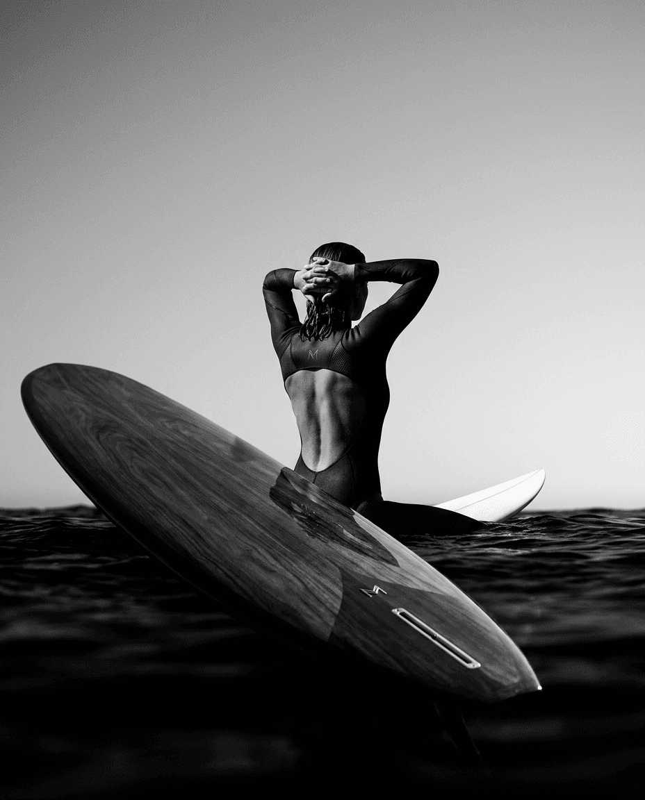 Silhouetted surfer in a powerful pose with a calm ocean behind.