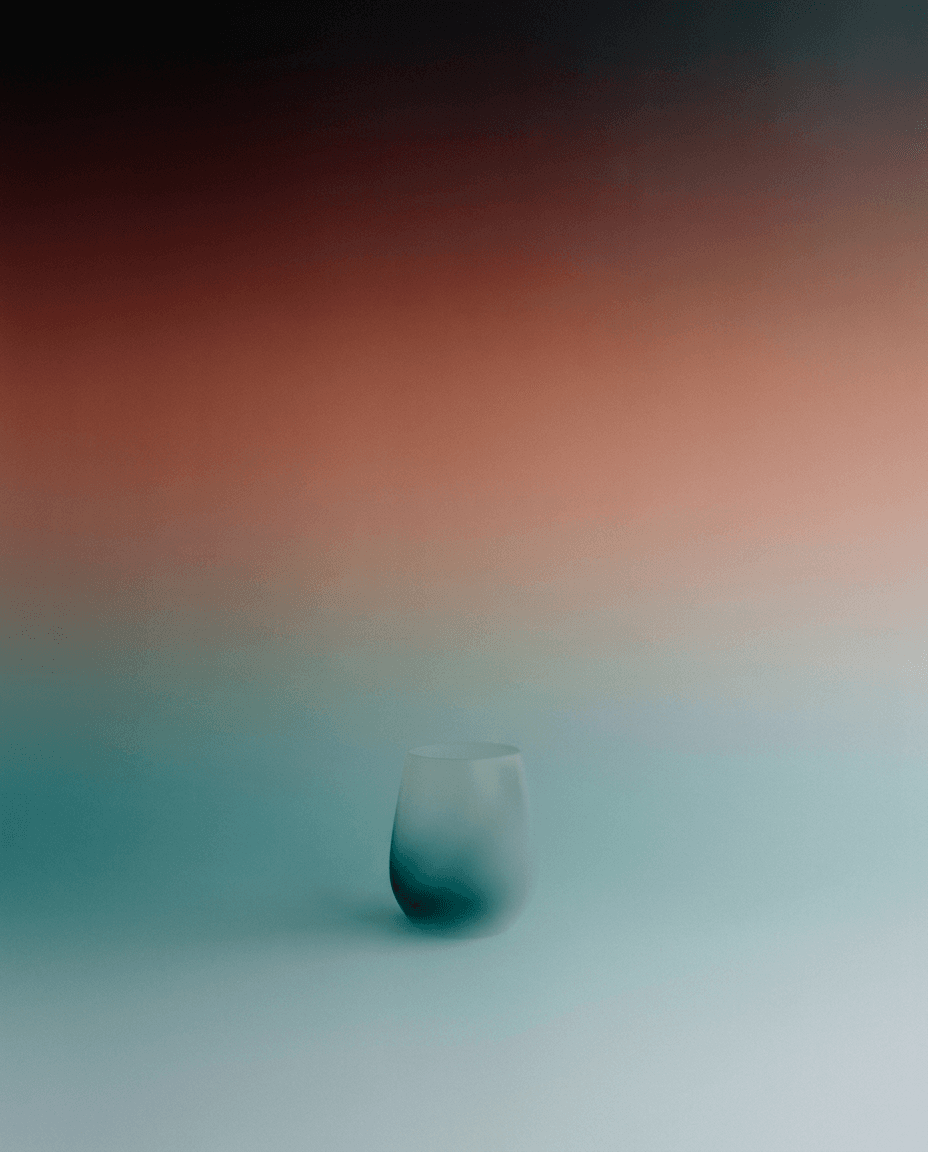 A frosted glass vessel on a gradient background of teal and peach.