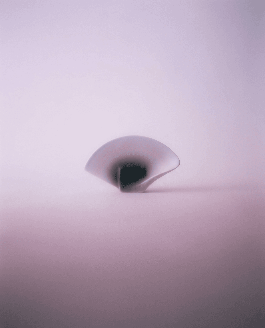 A translucent curved sculpture on a softly blurred pastel background.