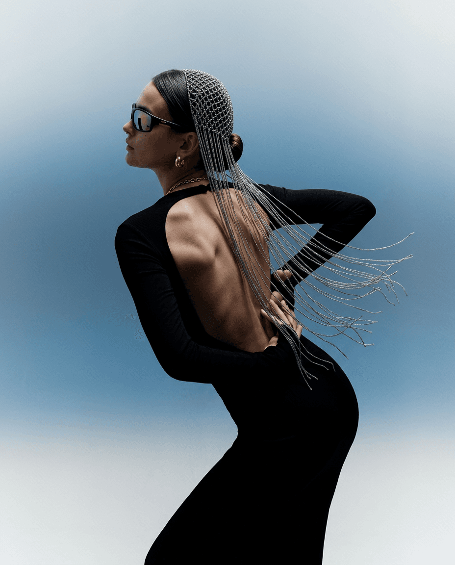 Model wearing a black dress with an open back and a headpiece, set against a blue background.