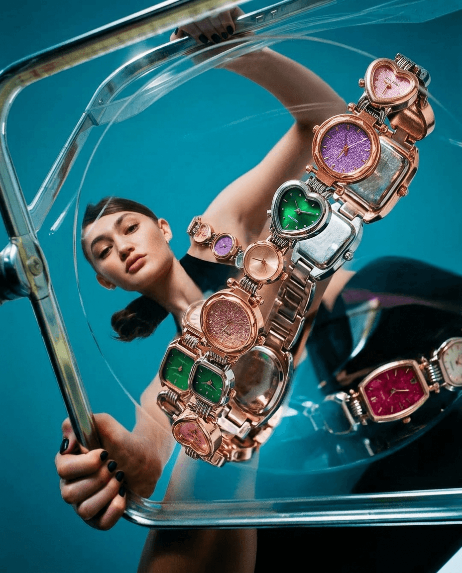 A model gazes through a transparent case holding colourful watches.