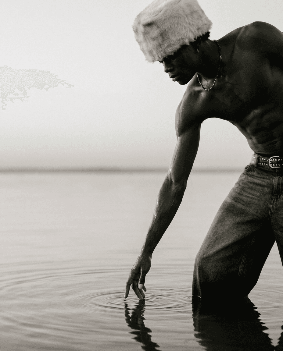 Black-and-white image of a man reaching into water, causing ripples.