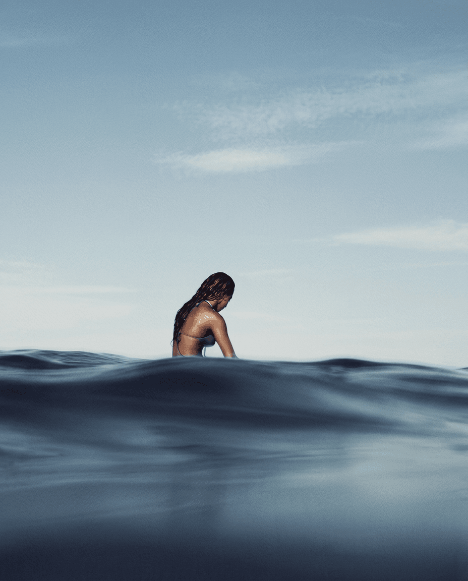 A solitary figure submerged in calm ocean waters with a blue and grey sky.