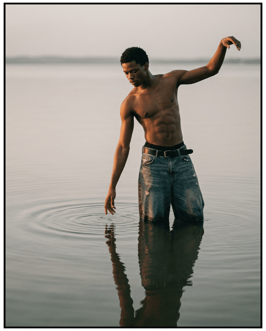 A man stands in shallow water, creating ripples with a serene expression.
