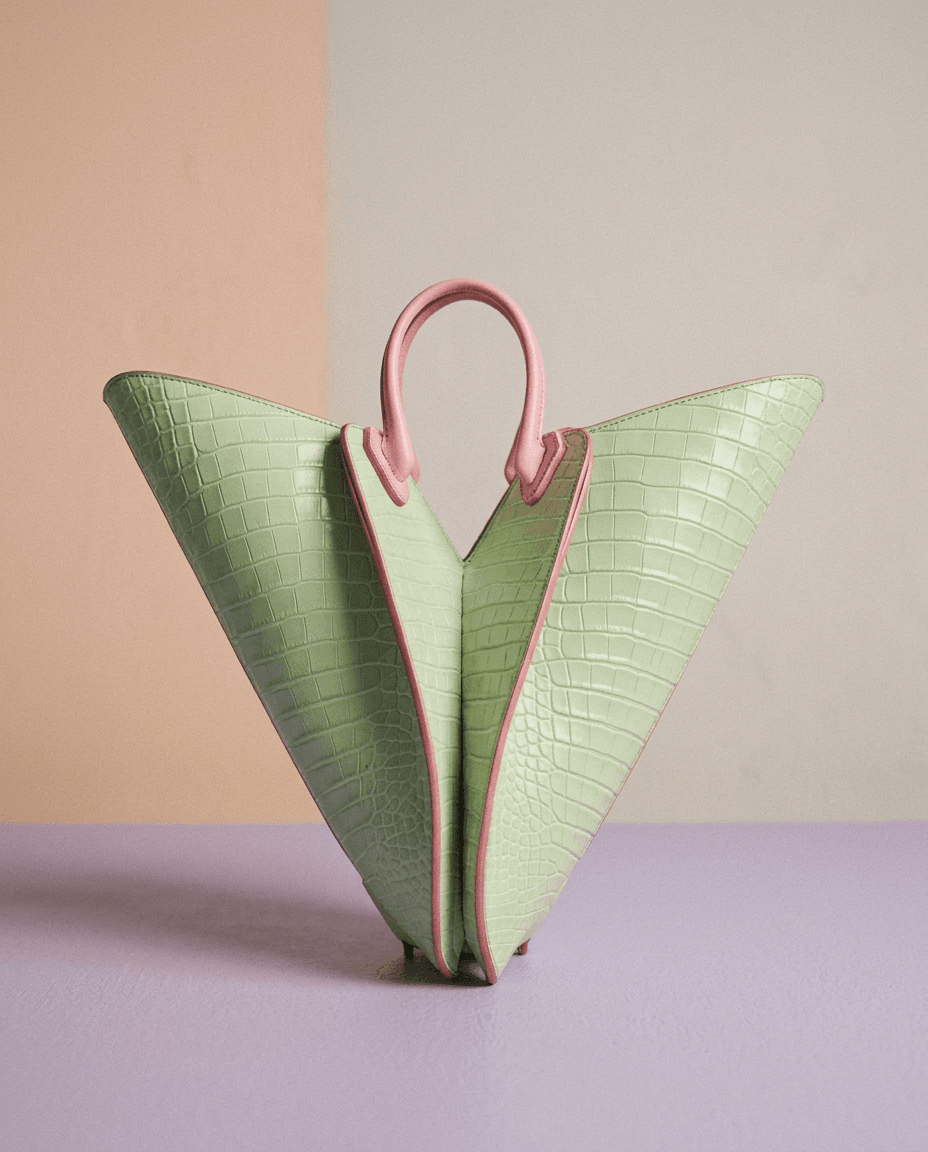 Pastel green handbag with pink accents on a soft background.