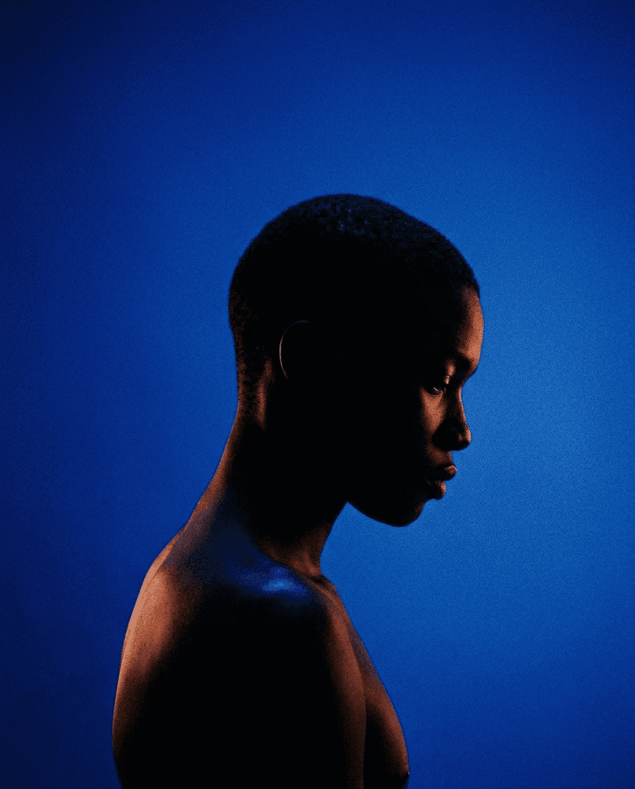 Profile of a young person illuminated against a deep blue background.