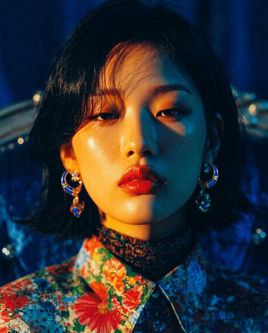 Young woman with striking features in a floral blouse and bold accessories.