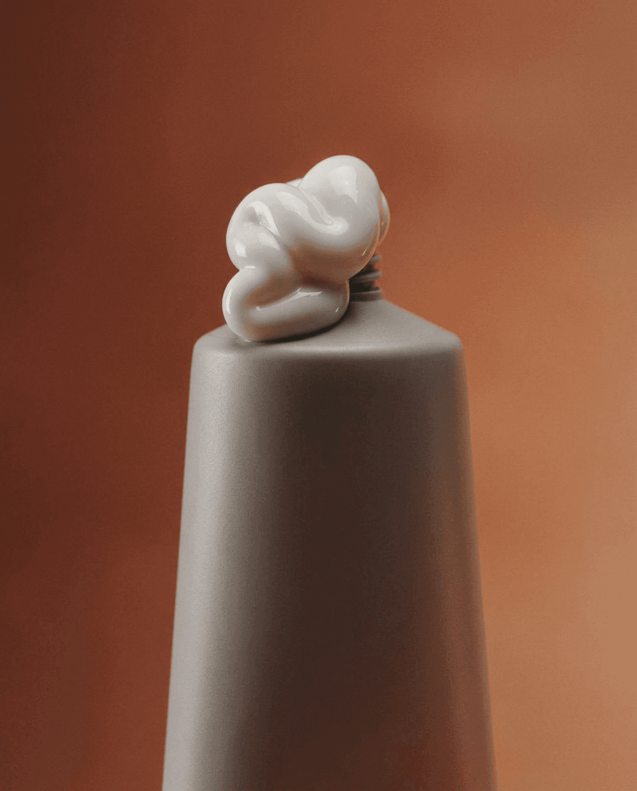 A gray ceramic vase with a white sculptural form on a warm, earthy background.