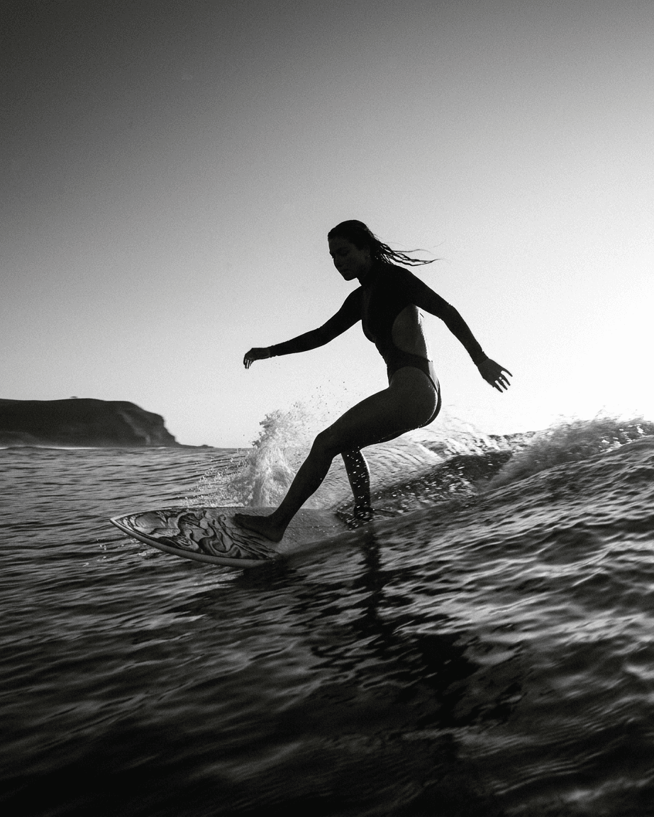 Silhouette of a surfer on a wave with a sunset backdrop.