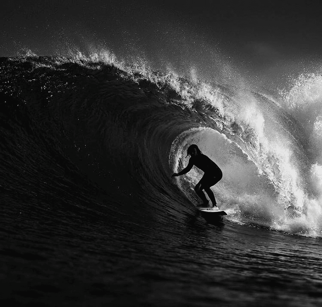 Black and white photo of a lone surfer on a powerful wave.