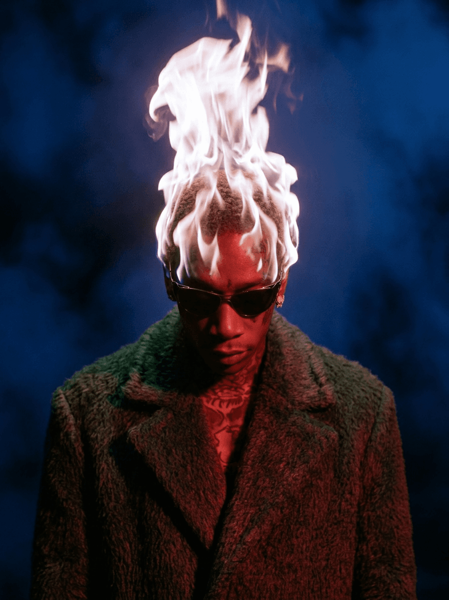 A man in sunglasses with flames coming from his head, set on a blue background.