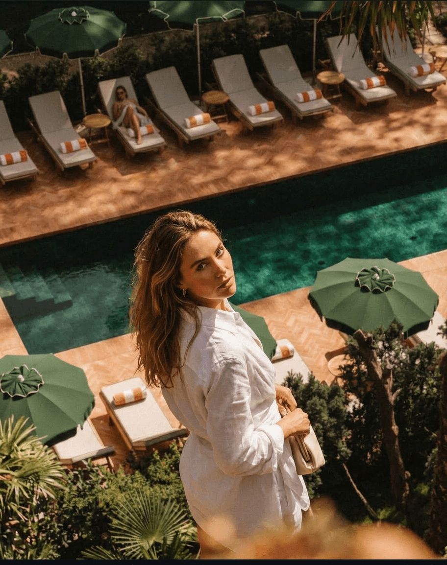 Woman in white shirt looking back at poolside with lounge chairs and umbrellas.