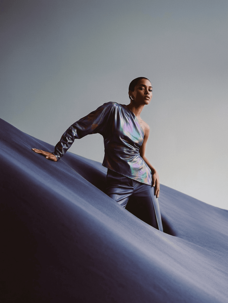 Model posing in high-fashion clothing on an undulating blue background.