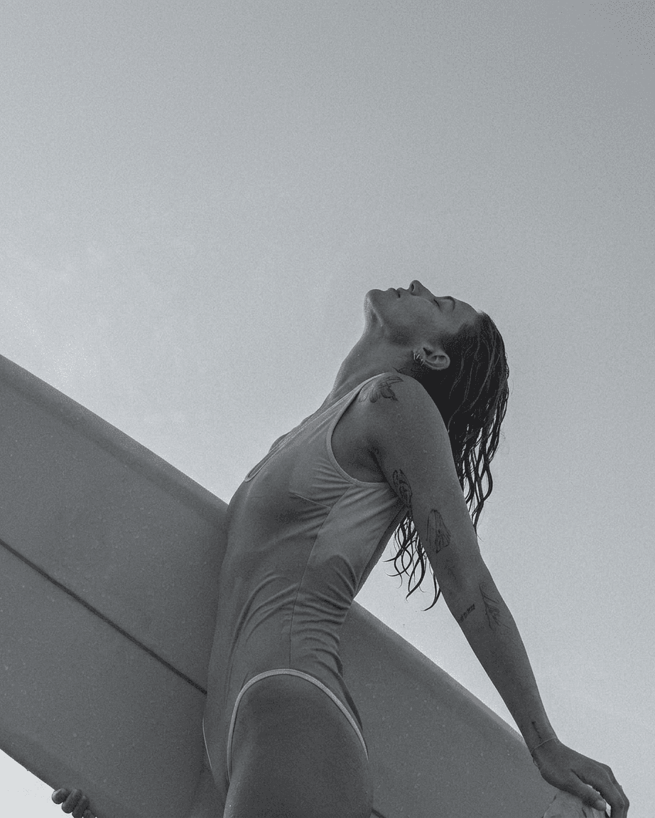 Black and white image of a woman with a surfboard in a simple background.