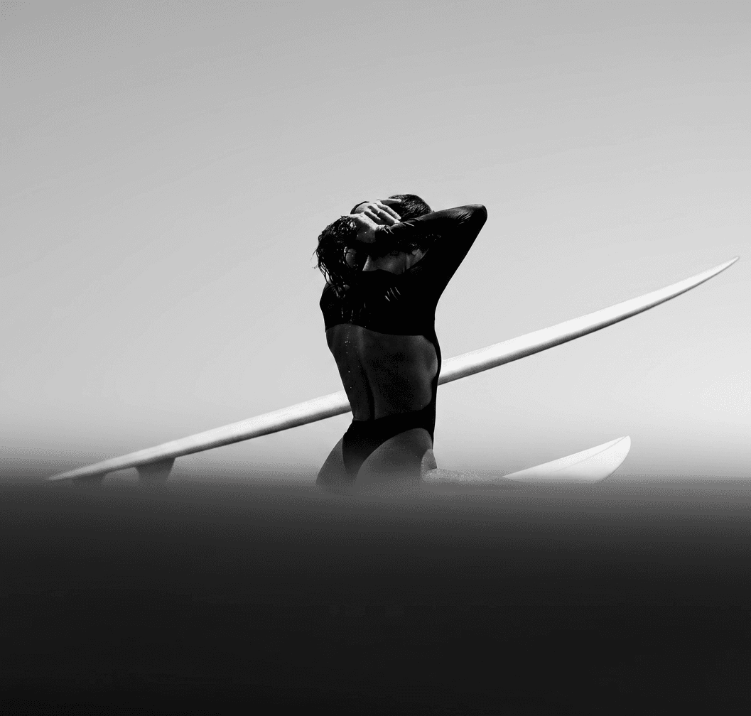 Black and white image of a lone surfer in a dynamic pose on the ocean.