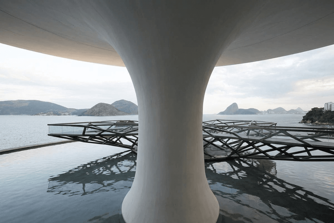 White structural column with a view of the sea and rocky mountains in the background.