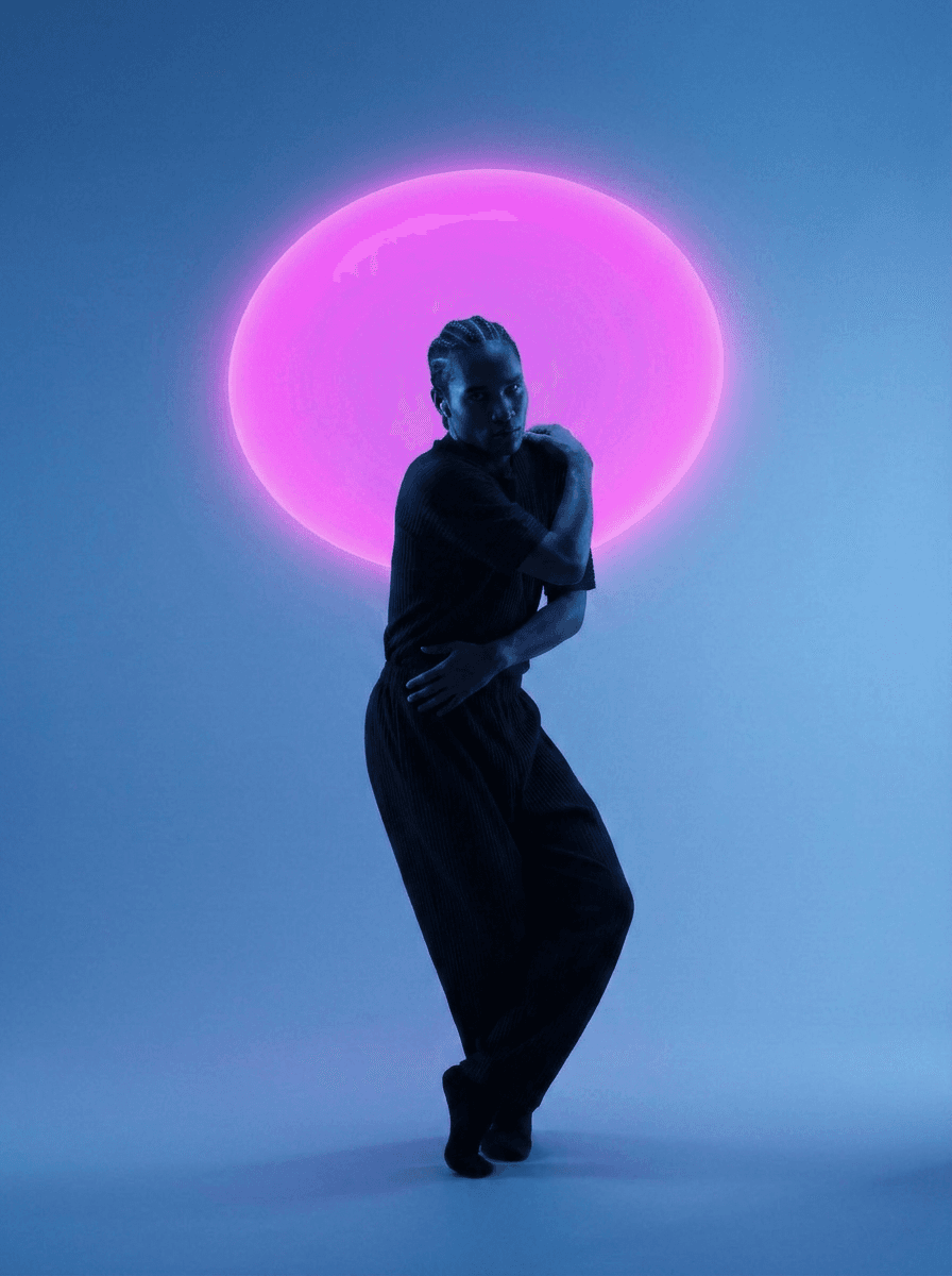 Silhouetted dancer in front of vibrant pink light and blue background.