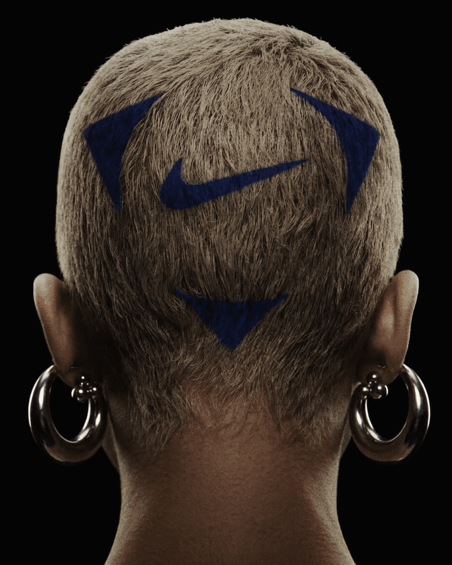 Close-up of a woman's shaved head with blue patterns and metallic hoop earrings.